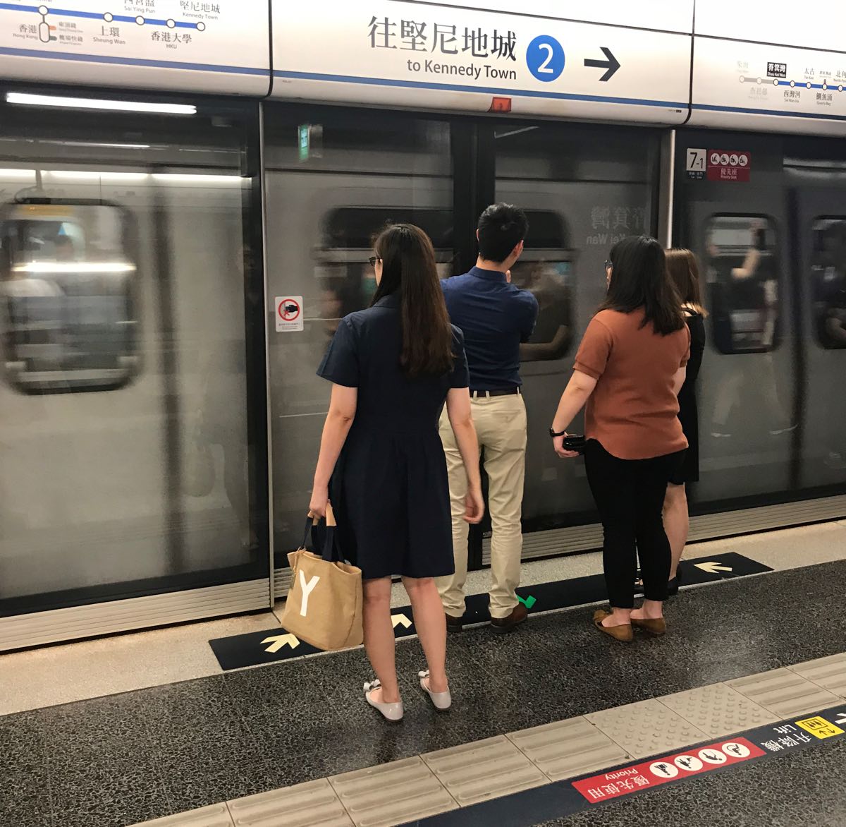 Photograph of people waiting behind glass doors for the train to stop